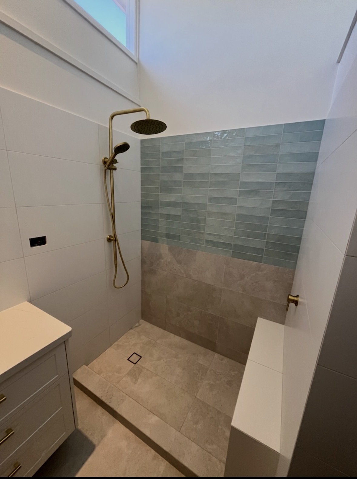 Shower recess with teal feature wall tiles, gold rain head and vanity